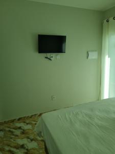 a bedroom with a bed and a flat screen tv on the wall at Pousada SB in Campo Formoso