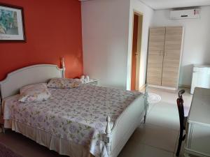 a bedroom with a white bed and an orange wall at Pousada Musleh in Rio Grande
