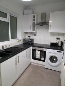 a kitchen with white cabinets and a washing machine at Cozy one bedroom flat in Chatham