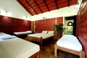 a room with two beds and two tables at Rainy Cloud Homestay - 1km Falls, Coffee Estate, Campfire, Home Food in Chikmagalūr