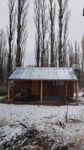 a log cabin with a snow covered roof in a field at Cabaña La 40 "Relax y descanso en zona de chacras" in Buta Ranquil +6 photos