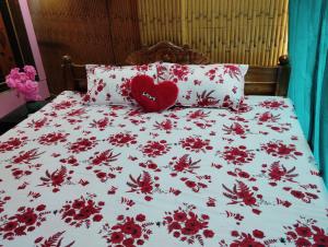 a bed with a red heart pillow and red flowers at MAMATA CROWN Inn in Bhubaneshwar +2 photos