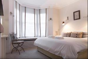 a bedroom with a bed and a chair and a window at Retreat to a Stylish 1 Bedroom Flat in Chelsea in London