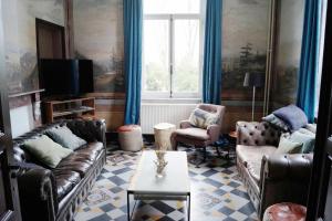 a living room with two leather couches and a tv at De Oude Pastorij in Maarkedal
