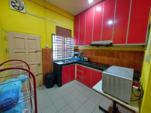 a kitchen with red and yellow cabinets and a sink at AIN's HOMESTAY in Kampong Mangka