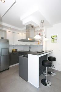 a kitchen with a counter and two stools in it at Apartman Ema in Podstrana