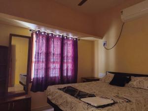 1 dormitorio con cama y cortina púrpura en DilsBreak HomeStay, en Kanyakumari 3 fotos más
