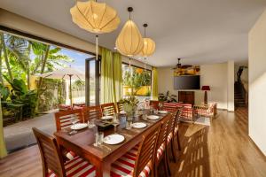 a dining room with a long wooden table and chairs at Antique Hoi An By S'cape Staycation in Tân Thành (1)