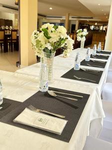 a long table with white flowers in a vase on it at فندق عنيزة الحديث in Unayzah