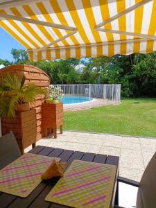 a patio with an umbrella and chairs and a pool at Tidousè Matnik in Sainte-Anne