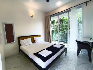 a bedroom with a bed and a desk and a window at Ecoark Farmstay in Cuncolim
