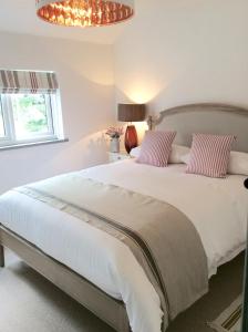 - une chambre avec un grand lit blanc et des oreillers roses dans l'établissement The Cottage, Yew Tree Farm Holidays, Tattenhall, Chester, à Tattenhall