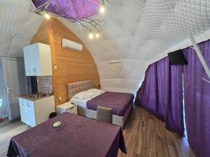 a bedroom with two beds in a room with purple curtains at Glamping Machakhela 2 in Ch'ik'unet'i