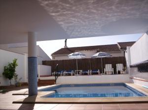 a swimming pool with chairs and umbrellas in a house at Casa Quercus con piscina privada in Cortes de la Frontera