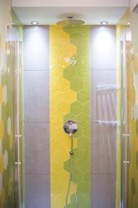 La salle de bains est pourvue d'une douche et d'un mur en carrelage jaune. dans l'établissement Relais del Corso, à Sorrente