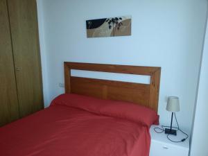 1 cama con colcha roja y una foto en la pared en RealRent La Antilla, en Moncófar