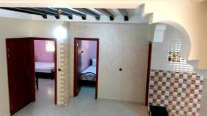 un couloir avec deux portes et une chambre avec un lit dans l'établissement Reem, à Temara
