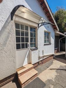 una porta d'ingresso di una casa bianca con scale di Yakhe self-catering Cozy styled 1 bedroomed a Edenvale