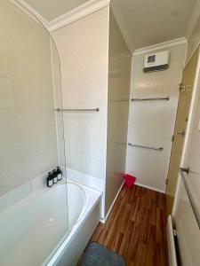 a small bathroom with a tub and a shower at Cosy queen room with ensuite toilet and private bathroom, shared spa pool in Dunedin