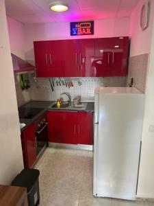 a kitchen with red cabinets and a white refrigerator at Apartamento Las Canteras in Las Palmas de Gran Canaria
