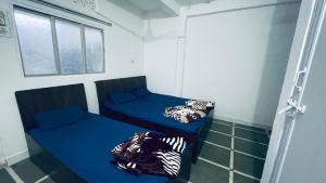 two beds in a small room with blue sheets at Home Stay - Maa Kaamal Deep in Surat