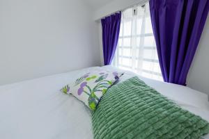 a bed with a green pillow and a window at Oakville Nezu by Tranova in Tokyo