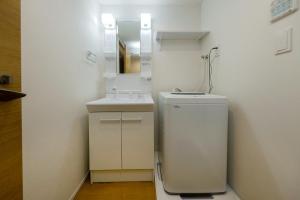 a white bathroom with a sink and a mirror at Oakville Nezu by Tranova in Tokyo