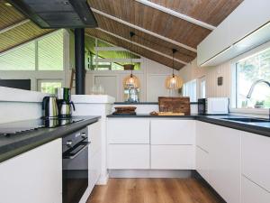 a kitchen with white cabinets and black counter tops at 4 star holiday home in Bindslev in Bindslev +47 photos