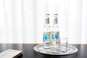 two bottles of water and glasses on a table at Im-Jaich Hotel Bremerhaven in Bremerhaven