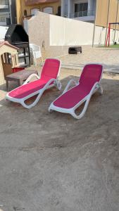 two empty lounge chairs sitting on the ground at فيلا السعادة بيتش درة العروس رملي وخاص in Durat  Alarous