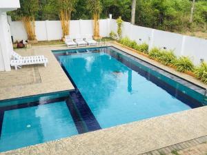 a swimming pool with blue water in a backyard at Wilroma Hotel&Resort in Anuradhapura