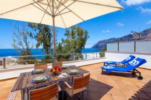 a patio with an umbrella and a table and chairs at Apartamentos Terrazas Los Gigantes by Suncanarias in Acantilado de los Gigantes