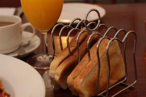 a sandwich on a rack on a table with a glass of orange juice at Abbey Grange Hotel in Nuneaton