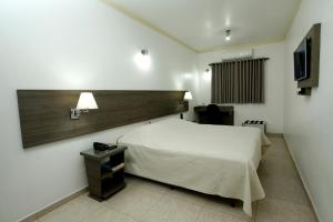 a bedroom with a white bed and a wooden headboard at Hotel Match Point in São Carlos +17 photos