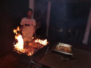 坦加拉Helios Beach Resort的火烤架上的男人烹饪食物