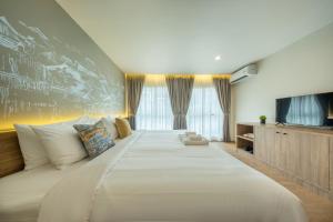 a large white bed in a room with a tv at Ralph Poshtel Sukhumvit in Bangkok