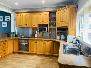 a kitchen with wooden cabinets and a sink and a microwave at Rose Garden Retreat in Timboon