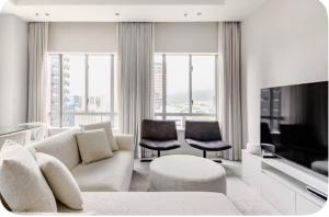 a living room with a couch and chairs and a television at The Cozy Luxe Apartment in Cape Town
