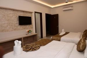 a hotel room with two beds and a flat screen tv at Hotel Golden Palace Ayodhya in Ayodhya
