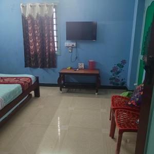 Una habitación con una cama, una mesa y un televisor. en Waves Homestay, en Pondicherry