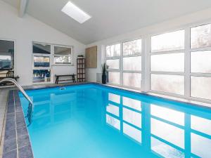 a swimming pool with blue water in a room with windows at 12 person holiday home in Væggerløse-By Traum in Marielyst
