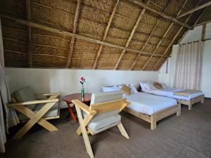 にあるBugoma Palms Resort Sand Beachのベッド2台、テーブル、ベッド1台、ソファが備わる客室です。