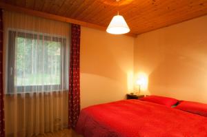 a bedroom with a red bed and a window at Casa al Lago di Carezza - Dolomiti in Carezza al Lago
