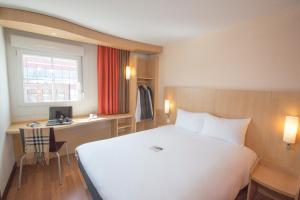 Habitación de hotel con cama blanca grande y escritorio. en ibis Lille Lomme Centre, en Lomme