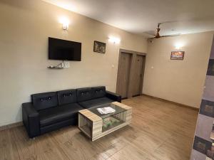 a living room with a black couch and a tv at Hotel Aurelia Heights in Jamshedpur