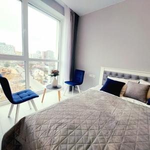 a bedroom with a bed and two chairs and a large window at Зелена тераса in Lviv