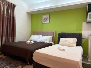 two beds in a room with green walls at The Viana Apartment 6 in Kota Bharu +19 photos