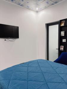 a bedroom with a blue bed and a flat screen tv at Nhà MIO in Khu Chi Lăng