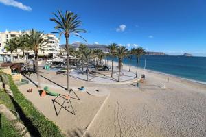 a sandy beach with palm trees and the ocean at Palatino Beach Albir in L'Alfas del Pi