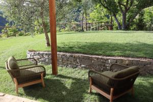 two chairs sitting in a yard with a stone wall at Agriturismo Radici by Miky in Monterosso al Mare